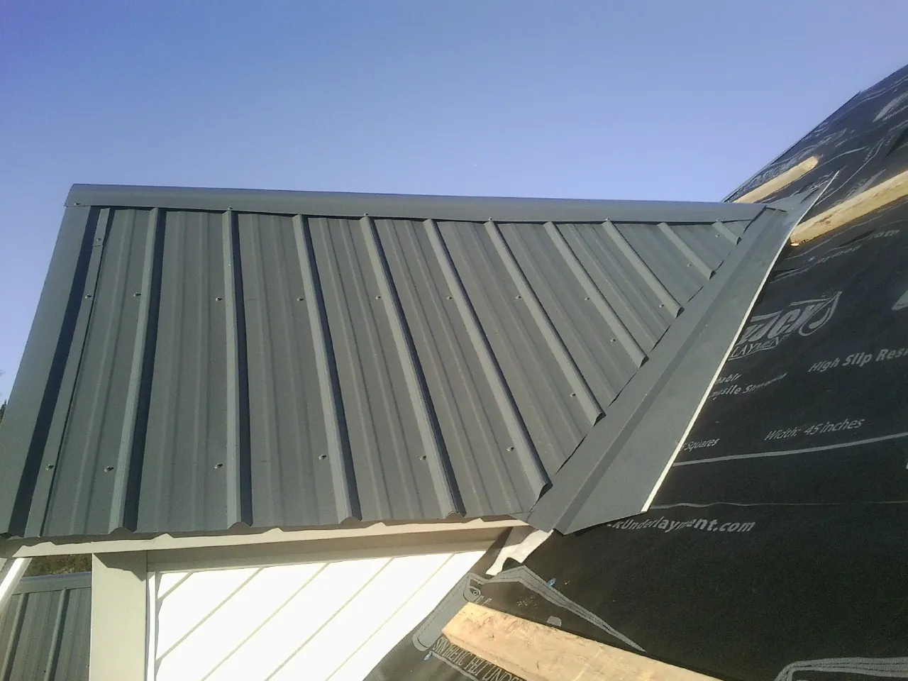 Gray metal roof panels going on over a garage gable in Camp Murray