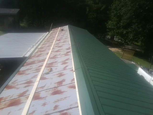 Old rusted panels beside newly installed green metal roofing — Wind Damage Roof Repair by Roofing Brothers in Camp Murray