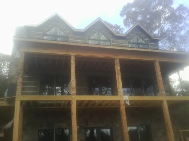 Dormers and porch framing on a large log home under construction — Roof Coating work by our crew in Camp Murray