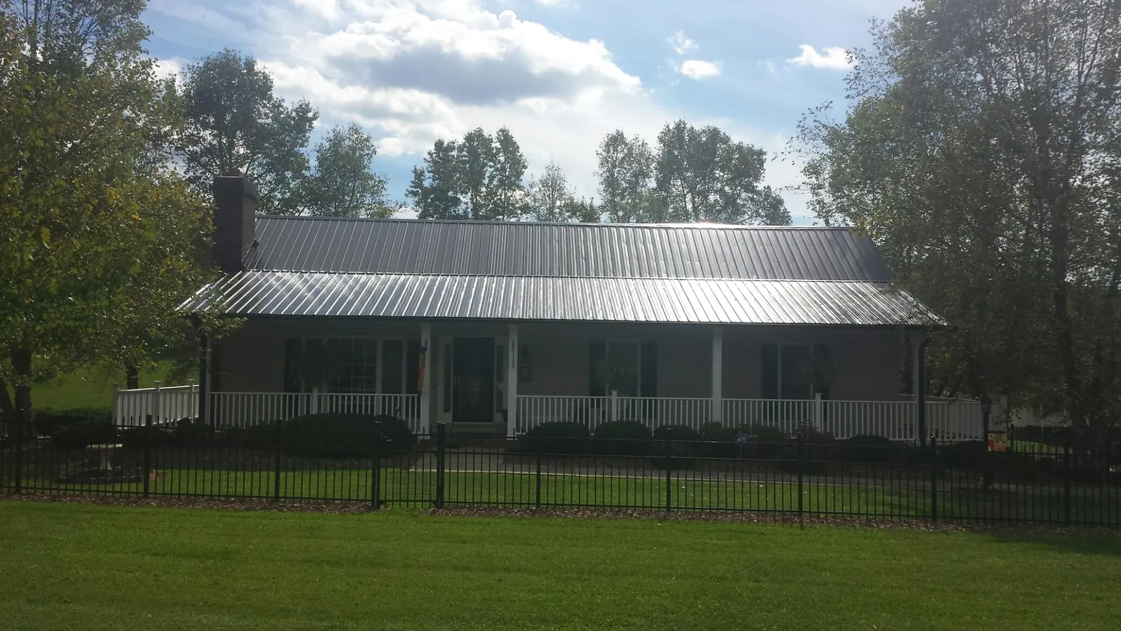 Gray metal roof on a brick ranch with a full width front porch — Gutter Guard Installation work by our crew in Camp Murray