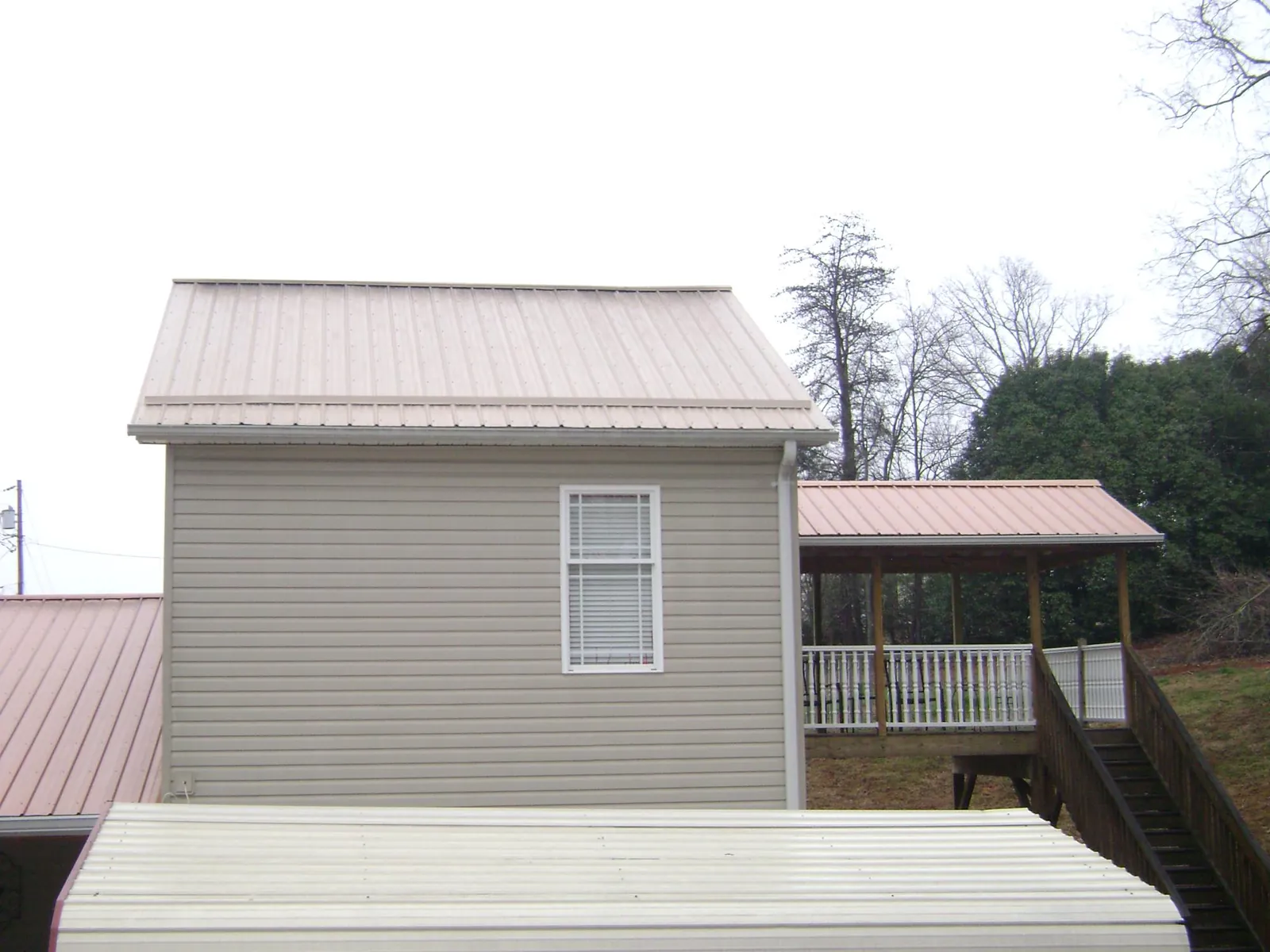 Tan metal roofs on a two story addition and attached porch, from a Roof Replacement job in Camp Murray