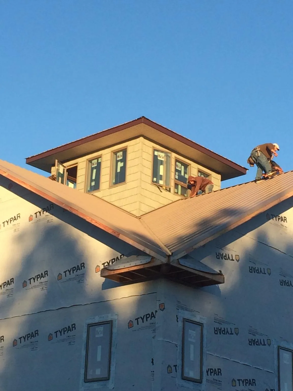 Roofers working around a rooftop cupola on a new metal roof at sunset — Roof Waterproofing in Camp Murray by Roofing Brothers